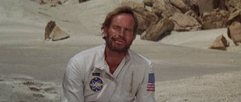 Movie still from “Planet of the Apes” (1968), directed by Franklin J. Schaffner – A man in a white shirt and a flag on his shirt; Close Up shot, Low angle