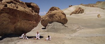 Movie still from “Planet of the Apes” (1968), directed by Franklin J. Schaffner – Two people sitting on the ground in the desert; Extreme Wide shot, Low angle