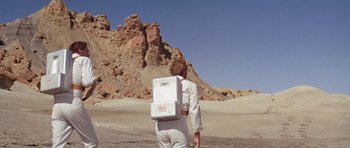 Movie still from “Planet of the Apes” (1968), directed by Franklin J. Schaffner – A person with a backpack walking in the desert; Wide shot, Low angle