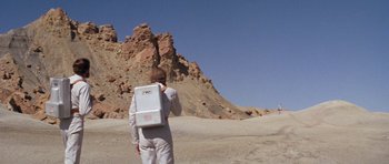 Movie still from “Planet of the Apes” (1968), directed by Franklin J. Schaffner – A man in a white suit is standing in the desert; Wide shot, Low angle