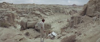 Movie still from “Planet of the Apes” (1968), directed by Franklin J. Schaffner – A man standing on top of a hill with a box; Extreme Wide shot, High angle