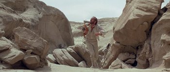Movie still from “Planet of the Apes” (1968), directed by Franklin J. Schaffner – A man is walking through the desert with a guitar; Wide shot, Low angle