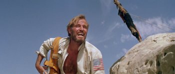 Movie still from “Planet of the Apes” (1968), directed by Franklin J. Schaffner – A man with a flag on his shirt is laughing; Medium shot, Low angle