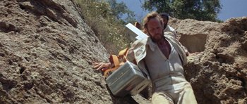 Movie still from “Planet of the Apes” (1968), directed by Franklin J. Schaffner – A man is climbing up a rock wall with a metal box; Medium shot, Low angle