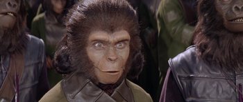 Movie still from “Planet of the Apes” (1968), directed by Franklin J. Schaffner – A man in a gorilla costume with a tie around his neck; Close Up shot, Over the shoulder angle