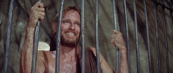 Movie still from “Planet of the Apes” (1968), directed by Franklin J. Schaffner – A man with a beard is behind a metal fence; Close Up shot, High angle