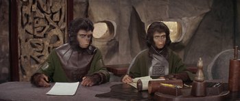 Movie still from “Planet of the Apes” (1968), directed by Franklin J. Schaffner – A couple of people sitting at a table; Medium shot, High angle