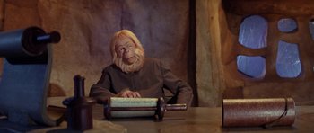 Movie still from “Planet of the Apes” (1968), directed by Franklin J. Schaffner – A man with a monkey mask sitting at a table; Medium shot, Low angle