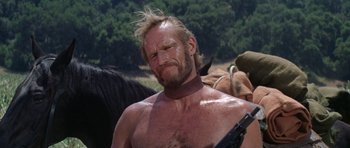 Movie still from “Planet of the Apes” (1968), directed by Franklin J. Schaffner – A man with a beard is holding a gun in his hand; Close Up shot, Low angle