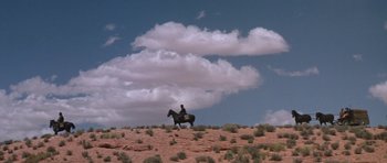 Movie still from “Planet of the Apes” (1968), directed by Franklin J. Schaffner – A man riding a horse on top of a hill under a cloudy blue sky; Extreme Wide shot, Low angle
