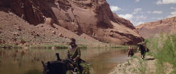 Movie still from “Planet of the Apes” (1968), directed by Franklin J. Schaffner – A man riding a horse down a river near a mountain; Wide shot, Low angle