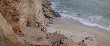 Movie still from “Planet of the Apes” (1968), directed by Franklin J. Schaffner – A man standing on top of a wooden platform near the ocean; Extreme Wide shot, High angle