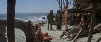 Movie still from “Planet of the Apes” (1968), directed by Franklin J. Schaffner – A group of people standing on top of a sandy beach; Wide shot, High angle