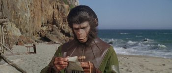 Movie still from “Planet of the Apes” (1968), directed by Franklin J. Schaffner – A man dressed as a monkey holding a piece of paper; Close Up shot, High angle