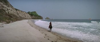 Movie still from “Planet of the Apes” (1968), directed by Franklin J. Schaffner – A man riding a horse on the beach near the ocean; Extreme Wide shot, High angle