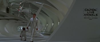 Movie still from “Planet of the Apes” (2001), directed by Tim Burton – A man in a white suit standing next to a white structure; Wide shot, High angle