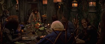 Movie still from “Planet of the Apes” (2001), directed by Tim Burton – A group of people sitting around a table with food; Medium shot, High angle