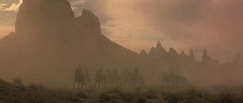 Movie still from “Planet of the Apes” (2001), directed by Tim Burton – A group of people riding horses through the desert; Extreme Wide shot, Low angle