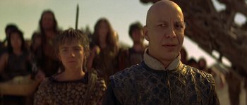 Movie still from “Planet of the Apes” (2001), directed by Tim Burton – A man with a bald head is standing in front of a group of people; Close Up shot, Over the shoulder angle