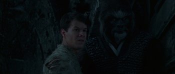 Movie still from “Planet of the Apes” (2001), directed by Tim Burton – A man standing next to a gorilla in a dark room; Close Up shot, Over the shoulder angle