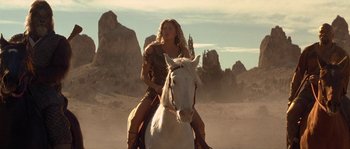 Movie still from “Planet of the Apes” (2001), directed by Tim Burton – A woman riding on the back of a white horse in the desert; Medium shot, Low angle