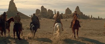 Movie still from “Planet of the Apes” (2001), directed by Tim Burton – A group of people riding on the backs of horses; Wide shot, Low angle