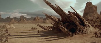 Movie still from “Planet of the Apes” (2001), directed by Tim Burton – A man running in the desert next to a bunch of trees; Extreme Wide shot, Low angle