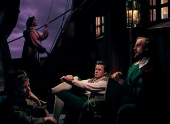 Movie still from “Plymouth Adventure” (1952), directed by Clarence Brown – A group of people sitting on a chair in a room; Wide shot, High angle