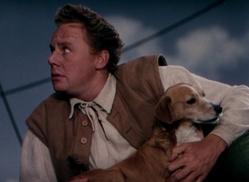 Movie still from “Plymouth Adventure” (1952), directed by Clarence Brown – A man holding a dog while sitting on a couch; Close Up shot, Low angle