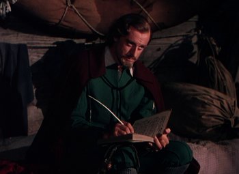 Movie still from “Plymouth Adventure” (1952), directed by Clarence Brown – A man sitting on the ground writing in a book; Medium shot, High angle