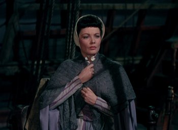 Movie still from “Plymouth Adventure” (1952), directed by Clarence Brown – A woman in a purple and white dress with a shawl around her neck; Medium shot, High angle