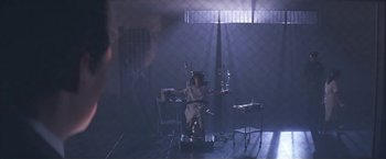 Movie still from “Point of No Return” (1993), directed by John Badham – A woman sitting in a chair in a dark room; Wide shot, High angle