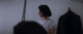 Movie still from “Point of No Return” (1993), directed by John Badham – A woman in a white t - shirt is looking at something; Close Up shot, Over the shoulder angle