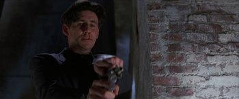 Movie still from “Point of No Return” (1993), directed by John Badham – A man holding a gun in a room with a brick wall; Close Up shot, Low angle