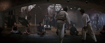 Movie still from “Point of No Return” (1993), directed by John Badham – A group of people sitting on the ground in a room; Wide shot, High angle