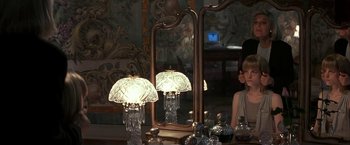 Movie still from “Point of No Return” (1993), directed by John Badham – A woman sitting in front of a mirror with two lamps on top of it; Medium shot, Over the shoulder angle
