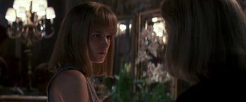 Movie still from “Point of No Return” (1993), directed by John Badham – A woman with a long hair and bangs looking into a mirror; Close Up shot, Over the shoulder angle