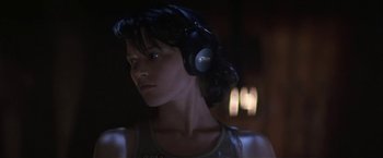 Movie still from “Point of No Return” (1993), directed by John Badham – A woman wearing headphones and looking into the distance; Close Up shot, Low angle