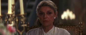 Movie still from “Point of No Return” (1993), directed by John Badham – An older woman wearing a white shirt and a gold necklace; Close Up shot, Over the shoulder angle