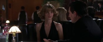 Movie still from “Point of No Return” (1993), directed by John Badham – A woman in a black dress sitting next to a man in a black suit; Close Up shot, Over the shoulder angle