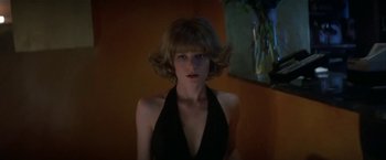 Movie still from “Point of No Return” (1993), directed by John Badham – A woman in a black dress in front of a painting; Close Up shot, Low angle