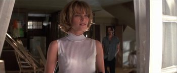 Movie still from “Point of No Return” (1993), directed by John Badham – A woman in a white top standing in front of a man; Medium shot, Low angle