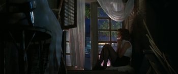 Movie still from “Point of No Return” (1993), directed by John Badham – A woman sitting in front of a large window; Wide shot, Low angle