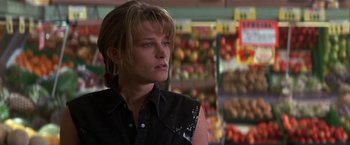 Movie still from “Point of No Return” (1993), directed by John Badham – A woman in a black shirt is in front of a fruit stand; Close Up shot, Low angle