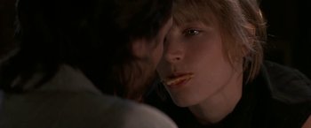 Movie still from “Point of No Return” (1993), directed by John Badham – A young man eating a piece of food while looking into the camera; Close Up shot, Over the shoulder angle