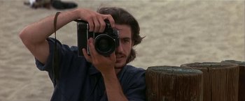 Movie still from “Point of No Return” (1993), directed by John Badham – A man holding a camera up to his face; Close Up shot, Low angle