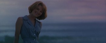 Movie still from “Point of No Return” (1993), directed by John Badham – A woman standing in front of a body of water at dusk; Medium shot, Low angle