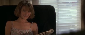 Movie still from “Point of No Return” (1993), directed by John Badham – A woman sitting in a chair holding a newspaper; Medium shot, Low angle