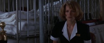 Movie still from “Point of No Return” (1993), directed by John Badham – A woman in a black and white suit standing in front of a fence; Close Up shot, Low angle