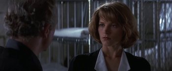 Movie still from “Point of No Return” (1993), directed by John Badham – A woman in black jacket and white shirt in a room; Close Up shot, Over the shoulder angle